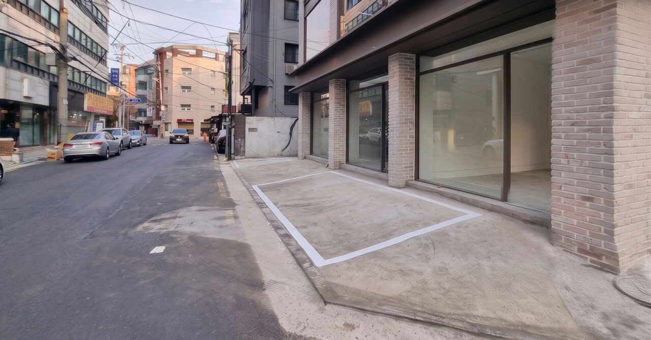 대수선 후 도로에 접한 1층 주차공간과 롱브릭 타일 마감 기둥, 대형 창호가 보이는 외관